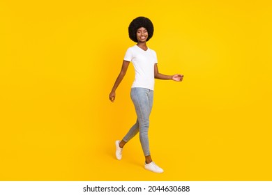 Full length photo of pretty friendly dark skin woman dressed white t-shirt smiling walking isolated yellow color background