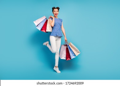 Full length photo of pretty lady carry many packs spree addicted shopaholic rejoicing shopping center wear dotted blouse white pants footwear isolated blue color background