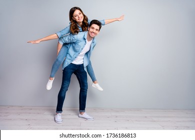 Full length photo pretty lady handsome guy couple carry piggyback meet adventures playful mood spread arms like wings wear casual denim shirts outfit isolated grey color background