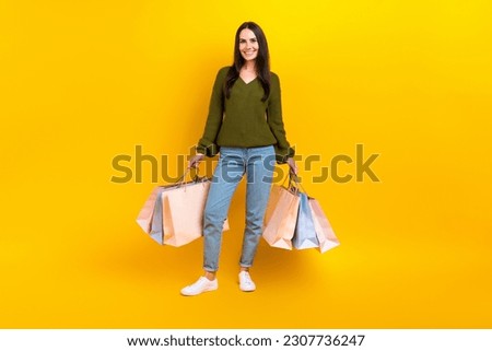 Full length photo of pretty sweet woman dressed khaki sweater holding shopping packages isolated yellow color background