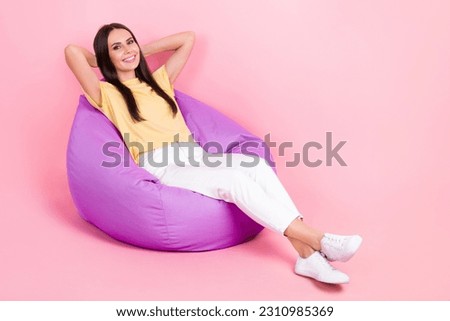 Full length photo of pretty sweet lady wear yellow t-shirt sitting bean bag arms behind head empty space isolated pink color background