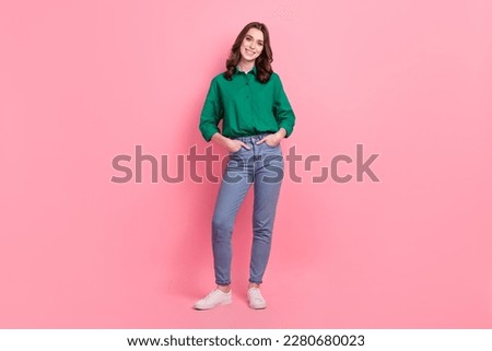Full length photo of satisfied lovely nice person wear jeans green shirt sneakers standing arms in pockets isolated on pink background
