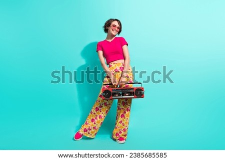 Full length photo of shiny adorable woman dressed flower print trousers enjoying boom box songs isolated teal color background