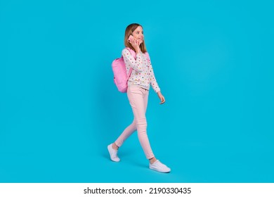 Full length photo of shiny cute little lady dressed dotted pullover rucksack communicating modern device isolated blue color background - Shutterstock ID 2190330435