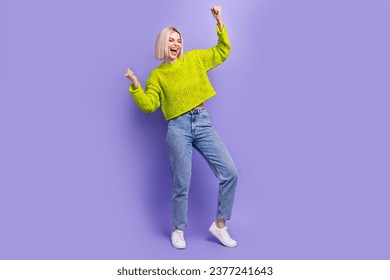Full length photo of shiny lucky lady wear green pullover rising fists empty space isolated purple color background - Shutterstock ID 2377241643