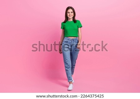 Full length photo of shiny pretty lady dressed green t-shirt smiling walking isolated pink color background