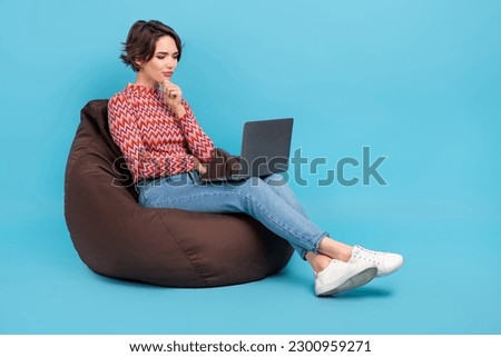 Full length photo of shiny thoughtful lady wear pink shirt sitting bean bag reading emails device empty space isolated blue color background
