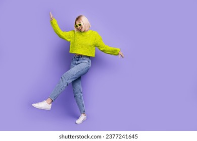 Full length photo of sweet adorable lady wear green pullover dark glasses dancing empty space isolated purple color background - Powered by Shutterstock