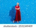 Full length photo of sweet charming senior lady wear red shiny dress arms folded smiling isolated blue color background