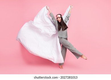 Full length photo of sweet charming lady sleepwear mask holding flying blanket walking smiling isolated pink color background