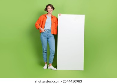 Full length photo of sweet cute woman wear denim jacket typing big modern device empty space isolated green color background - Powered by Shutterstock