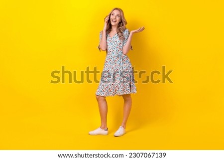 Full length photo of sweet dreamy lady wear flower print dress talking modern gadget empty space isolated yellow color background