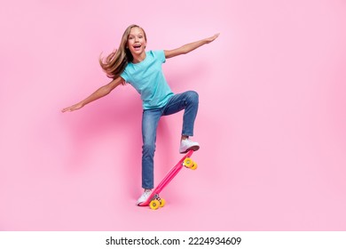 Full length photo of sweet excited small kid wear turquoise t-shirt riding skateboard empty space isolated pink color background - Powered by Shutterstock