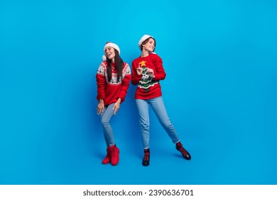 Full length photo of sweet shiny women santa elves wear ornament pullovers having fun x-mas disco isolated blue color background - Powered by Shutterstock