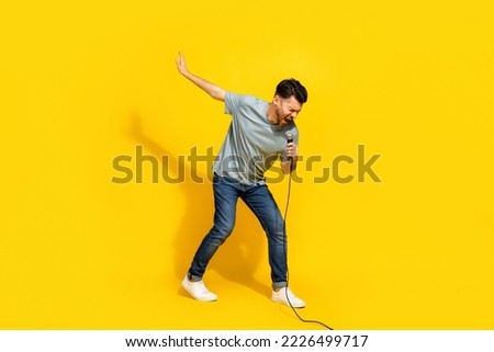 Full length photo of talented millennial artist stylish outfit relax rest sing lovely track empty space isolated on yellow color background