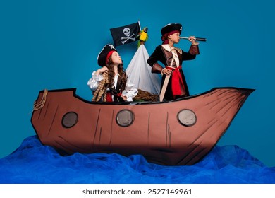 Full length photo of two little kids discovery spyglass dressed pirates costumes birthday party playing ship isolated on blue background - Powered by Shutterstock