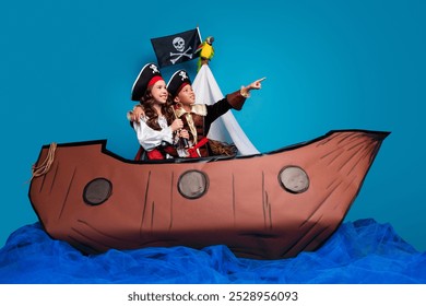 Full length photo of two little kids point look empty space wear pirates costumes birthday party playing ship isolated on blue background - Powered by Shutterstock