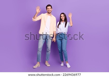 Full length photo of two positive idyllic people hold arms palms waving hi isolated on violet color background
