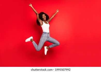 Full length photo of young afro girl happy positive smile jump up rejoice win lucky success isolated over red color background
