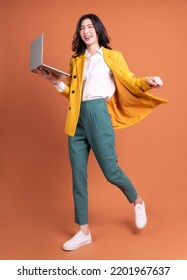 Full length photo of young Asian woman using laptop on background