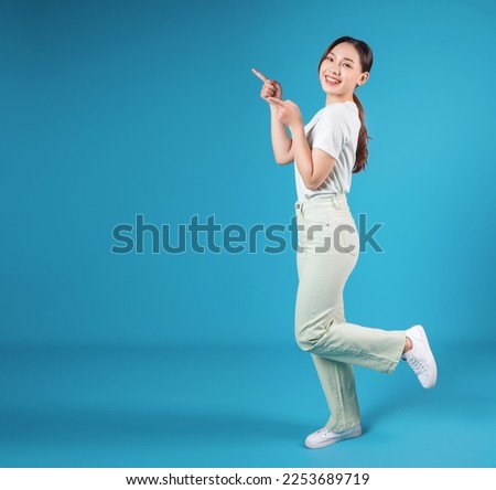 Full length photo of young Asian woman standing on blue backround