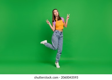 Full length photo of young cheerful funky woman make v-signs wear backpack isolated on green color background
