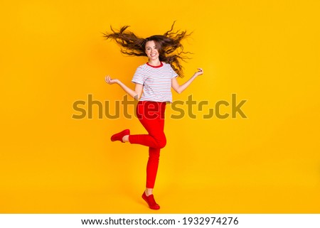 Full length photo of young cheerful woman happy positive smile fly air hair isolated over yellow color background