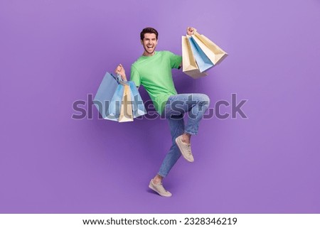Full length photo of young shopaholic guy hands hold shopping bags advertisement celebrate black friday offer isolated on purple background