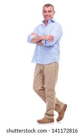 Full Length Picture Of A Casual Senior Man Standing With Arms Folded And Looking At The Camera. Isolated On White Background