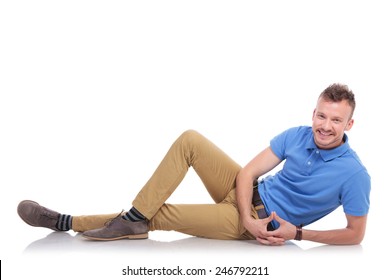 full length picture of a casual young man lying on the floor and smiling for the camera. on a white background