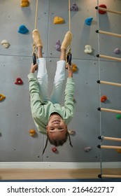 Full Length Portrait Of Active Black Child Hanging Upside Down On Sports Rings At Home And Having Fun