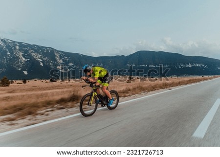 Full length portrait of an active triathlete in sportswear and with a protective helmet riding a bicycle. Selective focus  Imagine de stoc © 