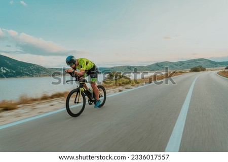 Full length portrait of an active triathlete in sportswear and with a protective helmet riding a bicycle. Selective focus  Foto stock © 