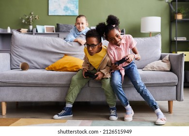 Full length portrait of African-American brother and sister playing video games at home together and fighting - Powered by Shutterstock