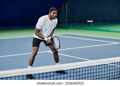 Full length portrait of agile black sportsman playing tennis at indoor court, copy space - Powered by Shutterstock