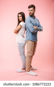 Full Length Portrait Of An Angry Young Couple Standing Back To Back Isolated Over Pink Background