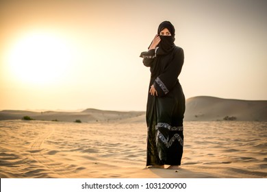 Full length portrait of Arab woman in burka clothing standing in the desert. - Shutterstock ID 1031200900