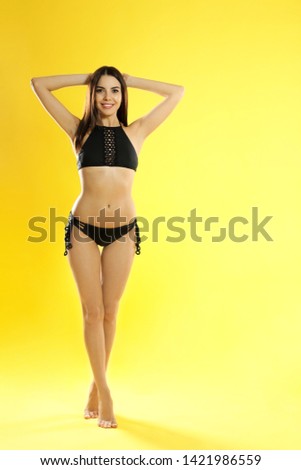 Full length portrait of attractive young woman with slim body in swimwear on color background. Space for text