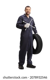 Full length portrait of an auto mechanic holding a tire and a lug wrench isolated on white background