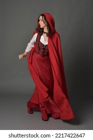 Full length portrait of beautiful brunette woman wearing red medieval fantasy costume with long skirt and flowing hooded cloak.
Standing pose with gestural hand poses, isolated on grey studio backgrou - Shutterstock ID 2217422647