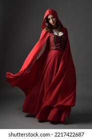 Full length portrait of beautiful brunette woman wearing red medieval fantasy costume with long skirt and flowing hooded cloak.
Standing pose with gestural hand poses, isolated on grey studio backgrou - Shutterstock ID 2217422687
