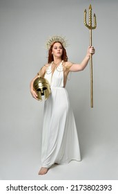 Full Length Portrait Of Beautiful Red Head Woman Wearing Long Flowing Fantasy Toga Gown With Golden Halo Crown Jewellery, Standing Pose   Isolated On A White Studio Background.