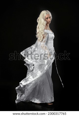 Full length portrait of beautiful women with long blonde hair, wearing white fantasy  princess  ball gown. standing walking pose. Isolated on black studio background.
