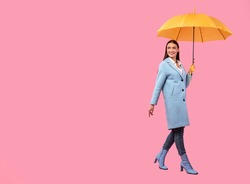 Full Length Portrait Of Beautiful Young Girl Holding Yellow Umbrella, Isolated Over Pastel Pink Studio Wall