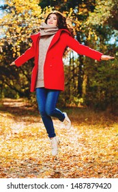 A Full Length Portrait Of A Beautiful Young Woman Jumping In An Autumn Forest. Lifestyle, Autumn Fashion, Beauty. 