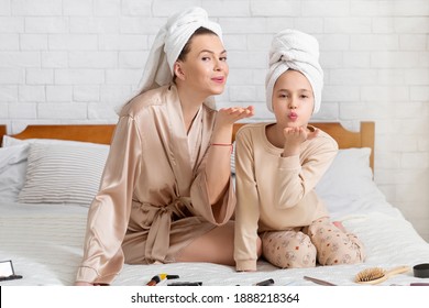 Full Length Portrait Of Beautiful Young Mother And Her Teen Daughter In Bath Towels Blowing Air Kisses On Bed At Home. Cute Girl And Her Mom Enjoying Family Beauty Spa Day