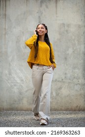 Full Length Portrait Of Beautiful Young Black Woman Walking Outside Talking On Her Mobile Phone