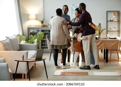 Full length portrait of big African-American family embracing while welcoming guests for dinner party at home