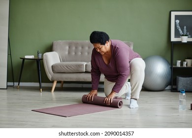 Full Length Portrait Of Black Senior Woman Unrolling Yoga Mat For Home Workout, Copy Space