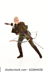 full length portrait of a blonde girl wearing green and brown medieval costume, holding a bow and arrow.
